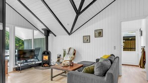 Ein modernes Wohnzimmer mit Kamin, einer Couch, einem Couchtisch und einem Fernseher.