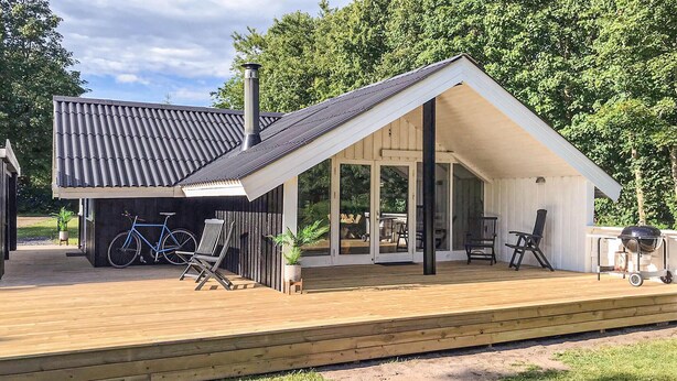 Ein modernes Haus mit einer Holzterrasse, einer Garage und einem überdachten Patio.