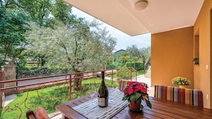 An outdoor patio with a wooden table, a bottle of wine, and a potted plant. - Beautiful apartment in Umag with WiFi (Umag)