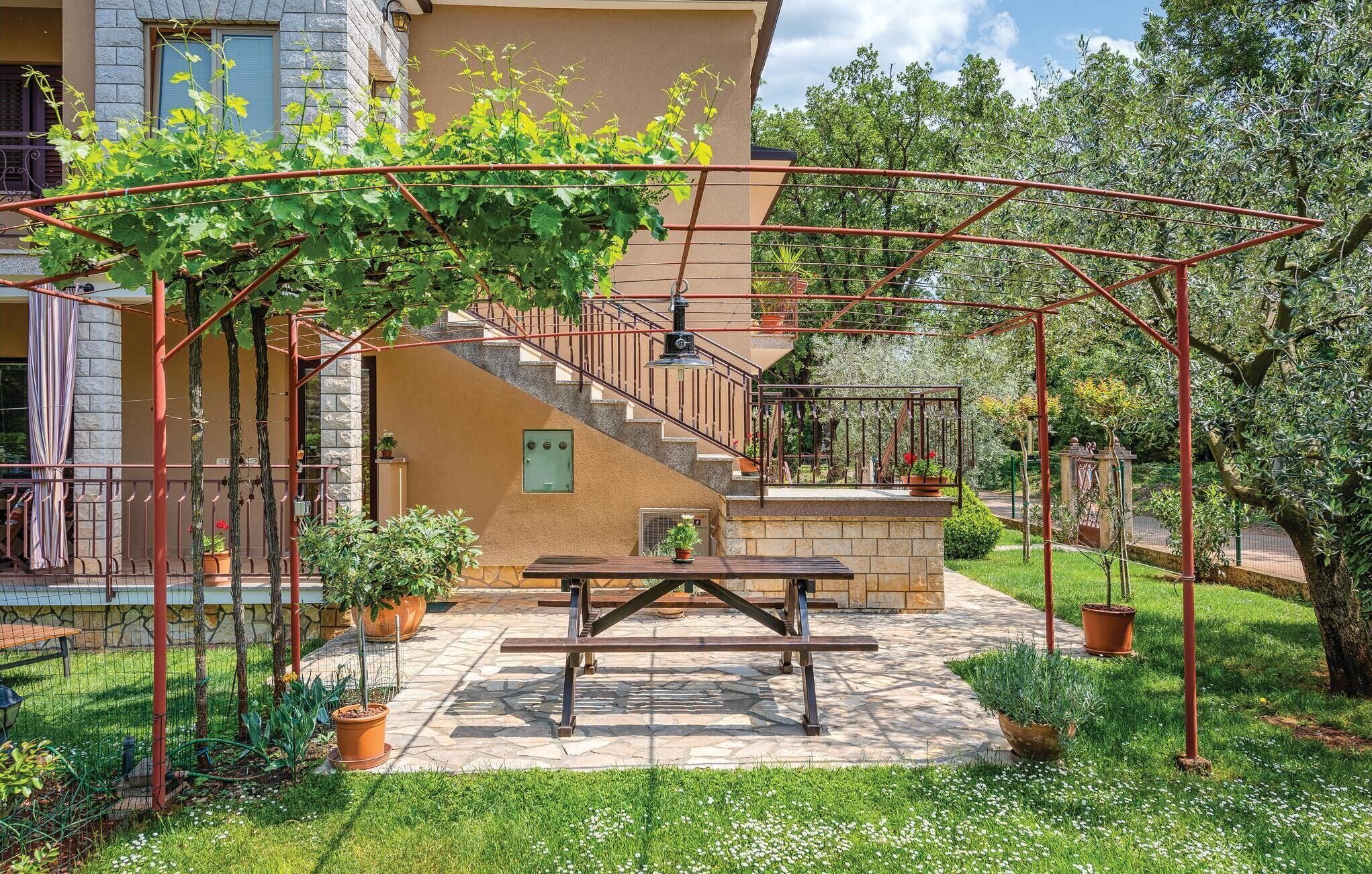 Ein Patio mit Pergola, Tisch und Kübelpflanzen.