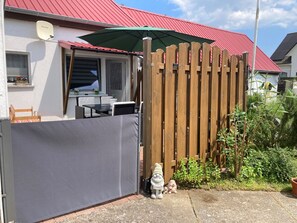 A fenced backyard with a patio table and chairs, a wooden fence, and a garden gnome statue. - Family Family Gießmann - Family Family Gießmann (Zempin)