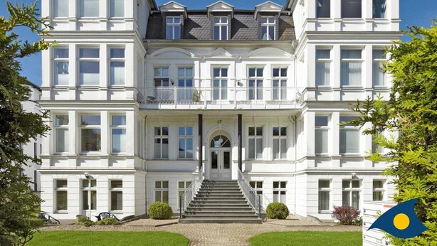 A large, symmetrical building with a central entrance, multiple windows, and a well-maintained lawn.