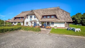 A two-story building with a thatched roof, a sign reading 'Mare,' and outdoor seating.