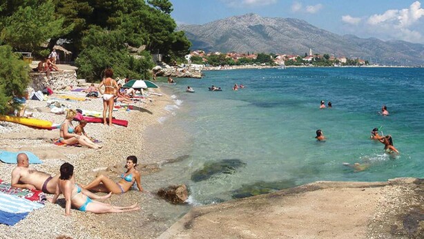 A beach with people sunbathing and swimming, surrounded by mountains and trees. - Beach front home in Orebic (Orebic)