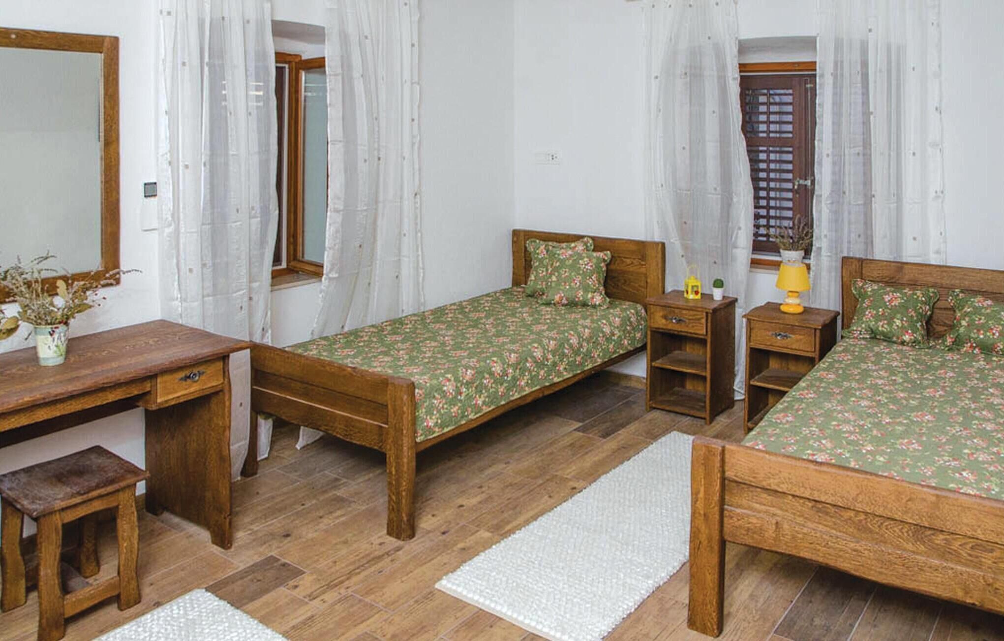 Une chambre à coucher avec deux lits en bois, un bureau en bois et un petit tabouret.