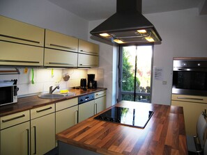 A modern kitchen with a central island, built-in oven, and a window providing a view of the outdoors.