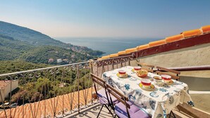 Ein Balkon mit Esstisch, mit Blick auf eine Küstenlandschaft.