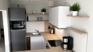 A compact kitchen with a built-in refrigerator, a coffee maker, and a small sink.