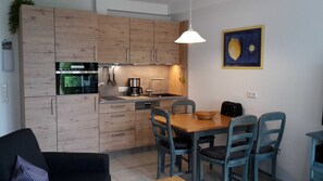 A modern kitchen with wooden cabinets, a built-in oven, and a dining area with a table and chairs.