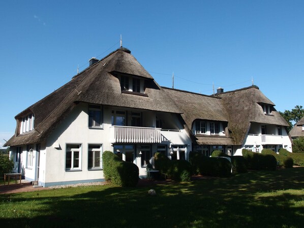 A large, two-story house with a thatched roof and a balcony.