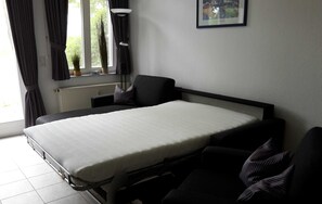 A compact room with a bed, a chair, and a radiator.