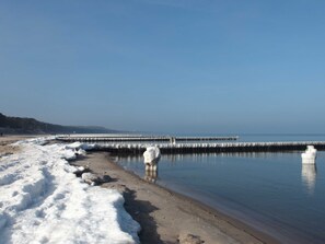 A beach with snow-covered sand and a calm sea.