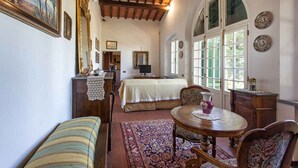 Una habitación con cama, escritorio, silla, mesa y ventana con persianas.