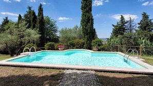 Piscina rectangular con borde curvo, rodeada de grava y delimitada por una barandilla metálica.