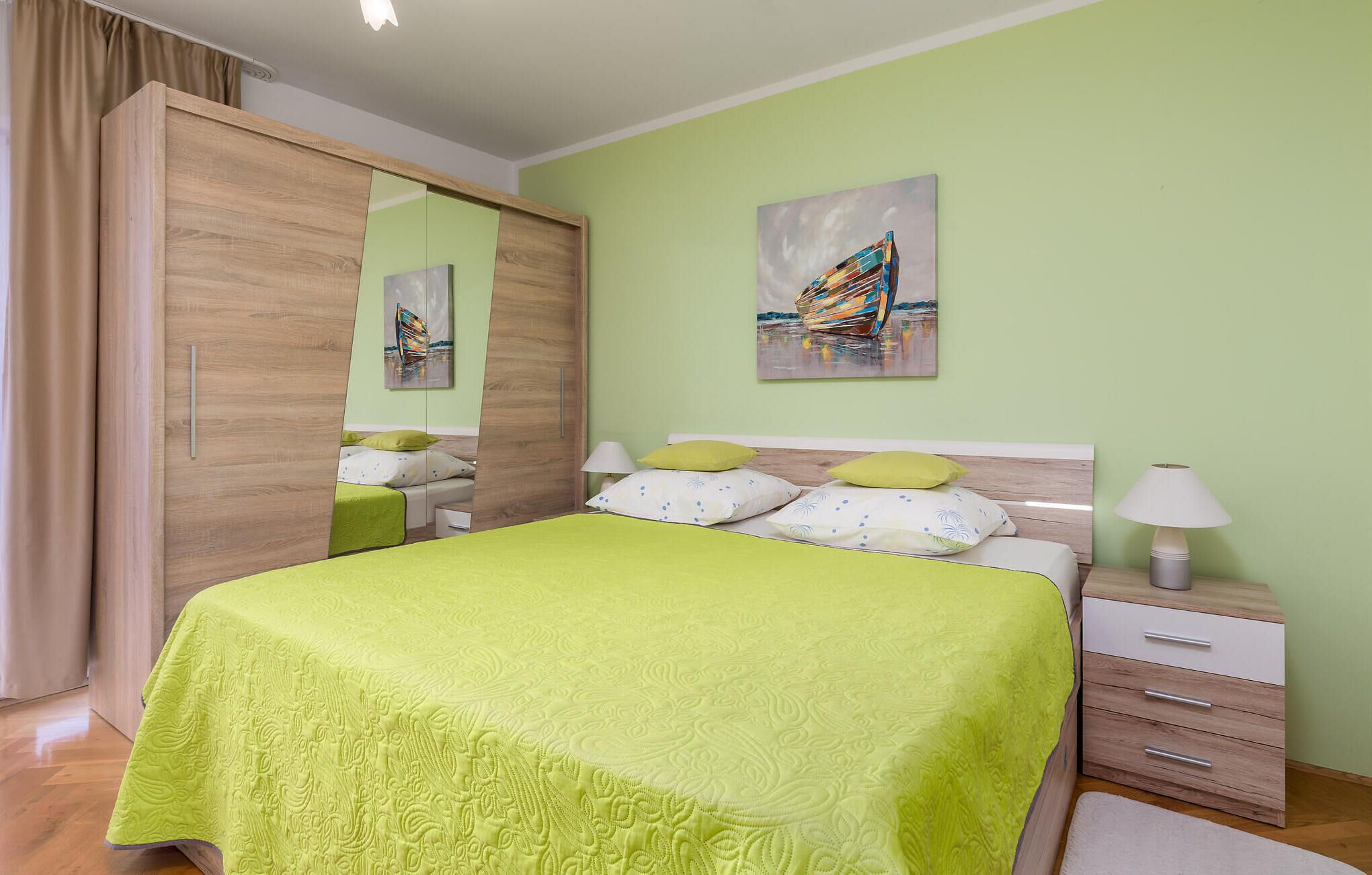 A bedroom with a bed, bedside tables, a wardrobe, and a painting on the wall.