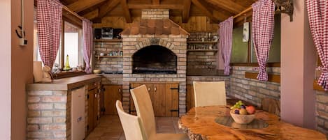 Una cocina rústica con horno de ladrillo, techo de madera y cortinas de cuadros.