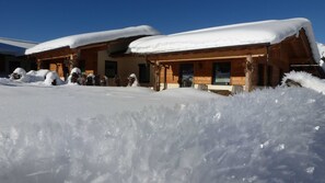 A wooden cabin with snow-covered roofs and a clear blue sky.