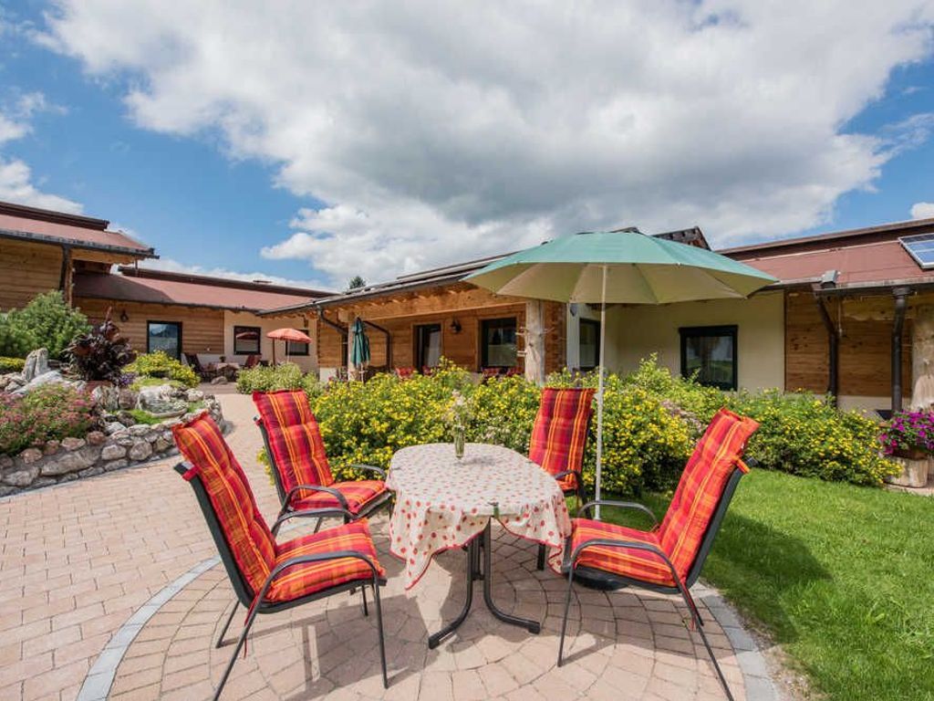 A patio with a round table, four chairs, and a green umbrella.