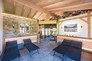 A cozy lounge area with stone walls, wooden beams, and a fireplace.