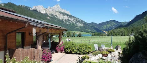 A chalet with a wooden exterior, a covered porch, and a view of mountains and a lake.