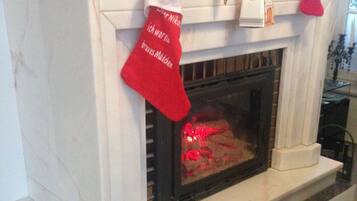 A fireplace with a Christmas stocking and a clock above it.