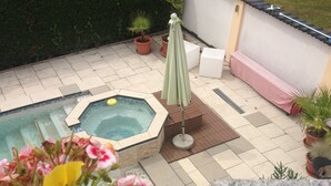 A backyard with a hot tub, a covered seating area, and potted plants. - Gästehaus Tante Tienchen (Rust)