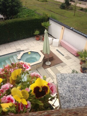 Ein Garten mit Whirlpool, überdachter Sitzgelegenheit und Pflanzen in Töpfen.
