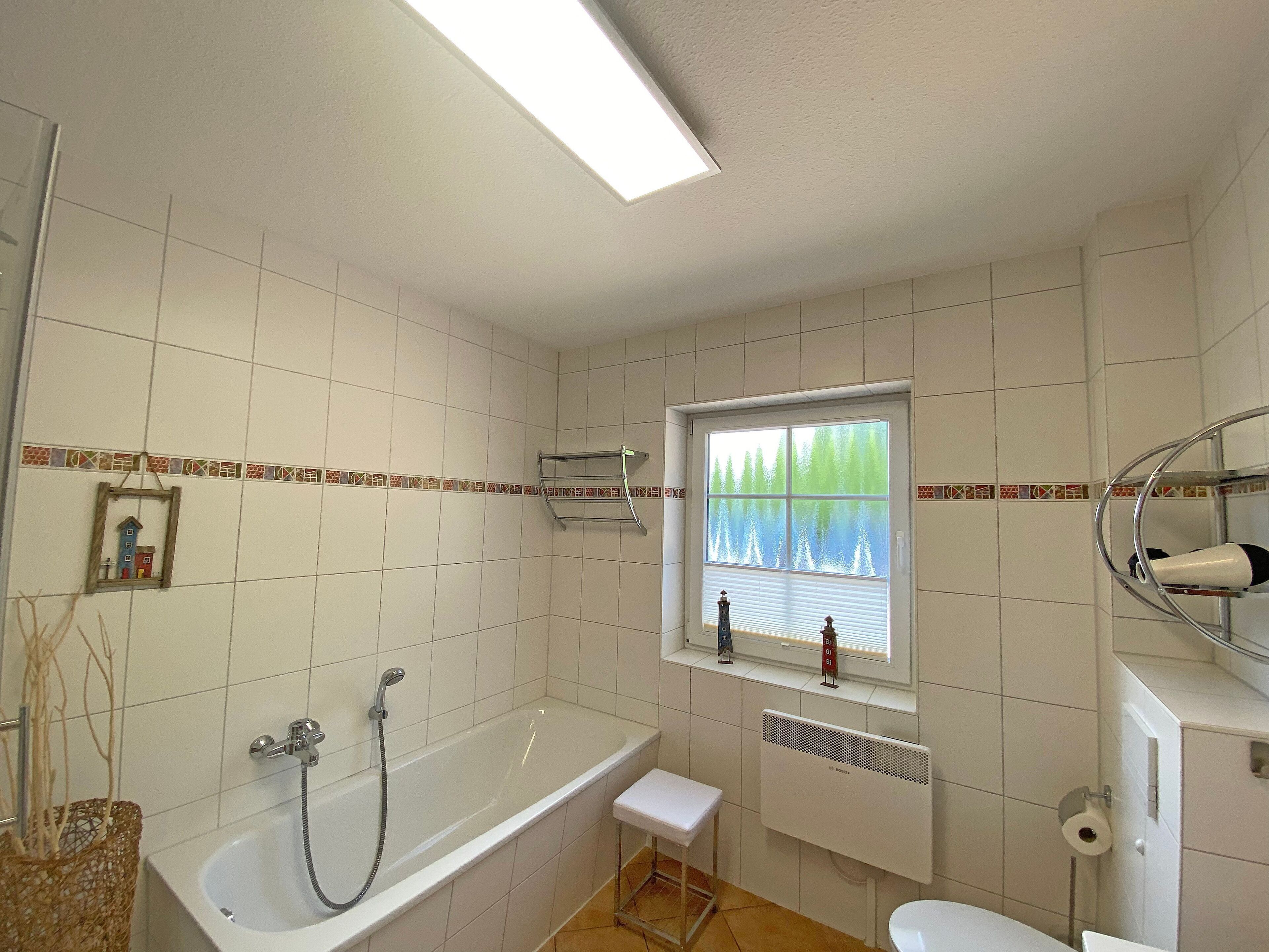 Een badkamer met een bad, een raam met uitzicht, een radiator en een toilet.