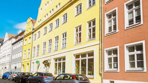 Una fila di edifici colorati con numerose finestre e una strada acciottolata.