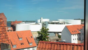 Vista di un paesaggio urbano con un mix di architettura tradizionale e moderna, incluso un edificio bianco distintivo con un design unico.