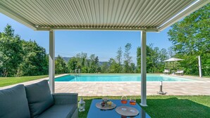 A covered outdoor area with a pool, a dining table with food and drinks, and a sofa. - Nice home in Camaiore LU (Camaiore LU)