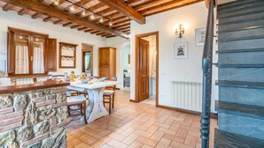 A kitchen with a stone wall, wooden cabinets, and a dining table. - Nice home in Camaiore LU (Camaiore LU)