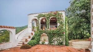Un bâtiment blanc doté de fenêtres en arc de cercle et d’un escalier menant à une terrasse.
