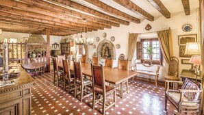 Un coin repas avec une table et des chaises en bois, un lustre et une cheminée en pierre.
