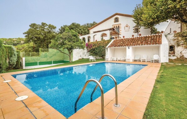 A swimming pool with two metal ladders, surrounded by a white building with a tiled roof and a green lawn. - Nice home in Arenys de Munt (Arenys de Munt)