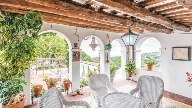 Un espace extérieur aménagé avec des meubles de jardin en osier, des plantes en pot et une vue sur le paysage.