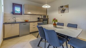 A modern kitchen with a dining table and chairs, a microwave, and a dishwasher. - Awesome home in Kavran with WiFi (Kavran)