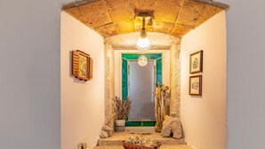A narrow hallway with a rustic stone archway, a green door, and a small altar with religious statues and a basket of bread. - Awesome home in Kavran with WiFi (Kavran)