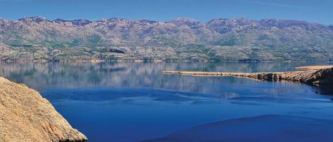 A calm lake with a rocky shoreline and mountains in the background.