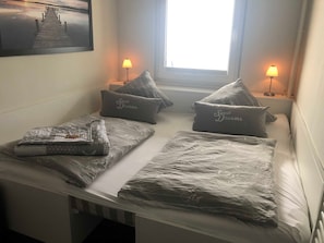 Uma cama de casal com vista para um cais, duas luminárias de cabeceira e almofadas com a inscrição 'Sweet Dreams'.