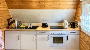 A compact kitchen with a wooden ceiling, a stove, a sink, and a small oven. - 2 bedroom nice home in Bad Lobenstein (Bad Lobenstein)