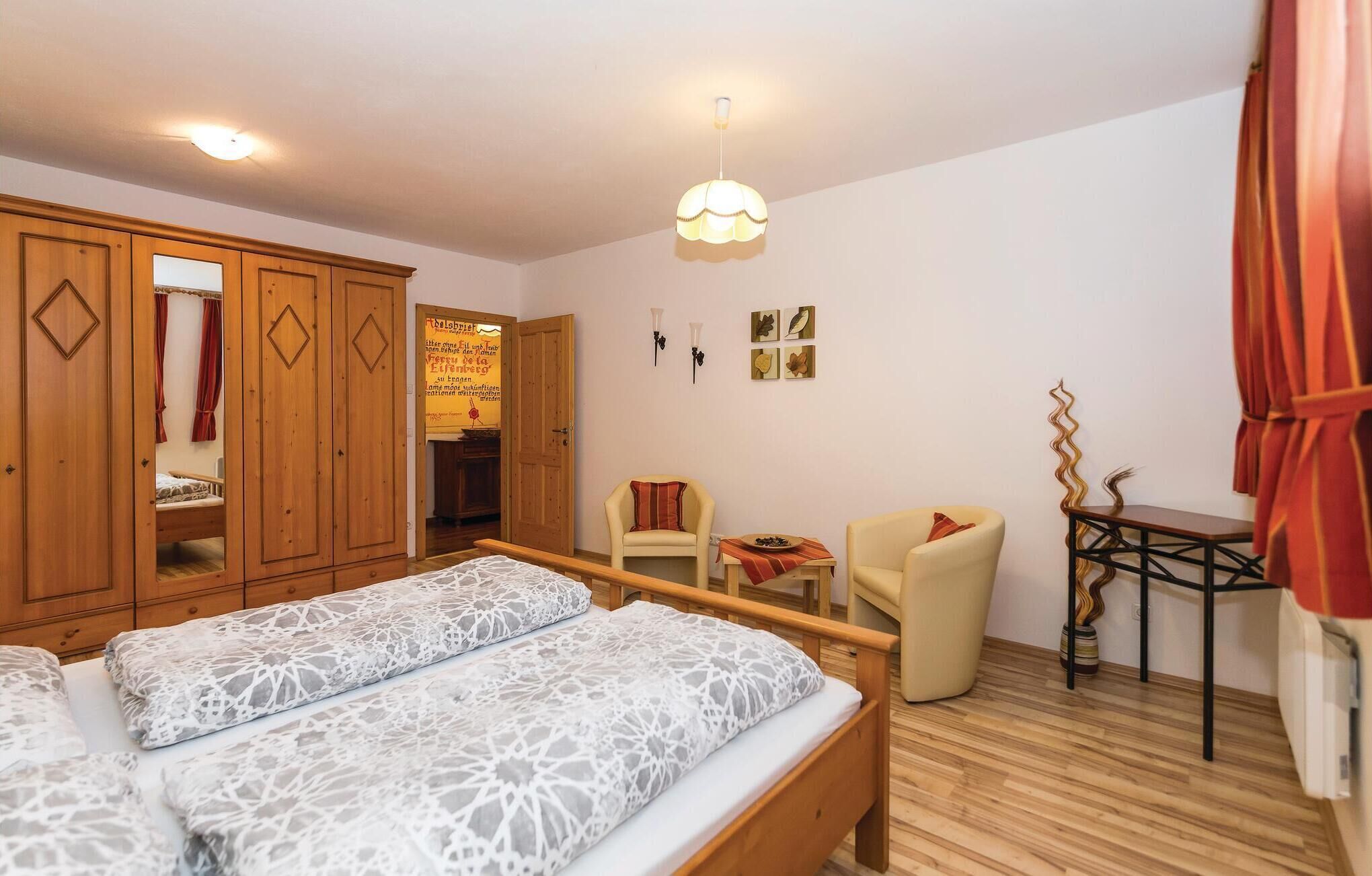 Een hotelkamer met twee bedden, een houten kledingkast, een kleine tafel met stoel en een wandlamp.