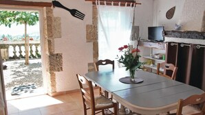 A dining area with a table and chairs, a TV on a shelf, and a view of the outdoors. - Gorgeous home in Lavardac with kitchen (Lavardac)