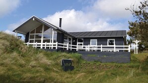 En moderne toetagers bygning med hvidt hegn, store vinduer og skorsten.