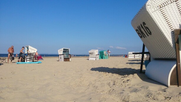 Una playa con varias cabañas, cielo despejado y el mar al fondo.