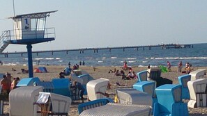 A beach with lounge chairs and a lifeguard tower.