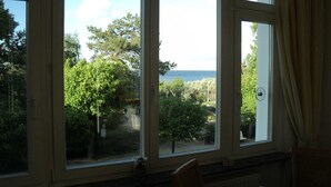 Una habitación con amplios ventanales que dan a un jardín y al mar.