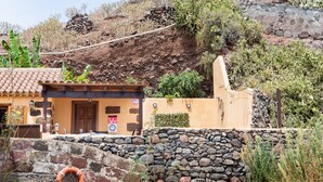 A rustic building with a tiled roof, a stone wall, and a lifebuoy hanging on the wall. - La casita de la playa with jacuzzi (Santa Cruz de Tenerife)