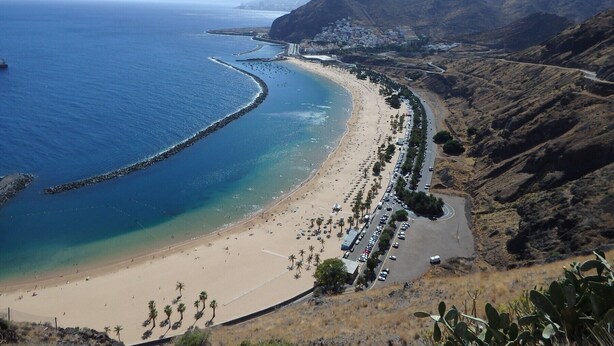 A coastal town with a long sandy beach, a rocky breakwater, and mountainous terrain in the background. - La casita de la playa with jacuzzi (Santa Cruz de Tenerife)