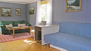 Ett vardagsrum med en blå soffa, en grön soffa, ett träbord och ett fönster med gardiner.